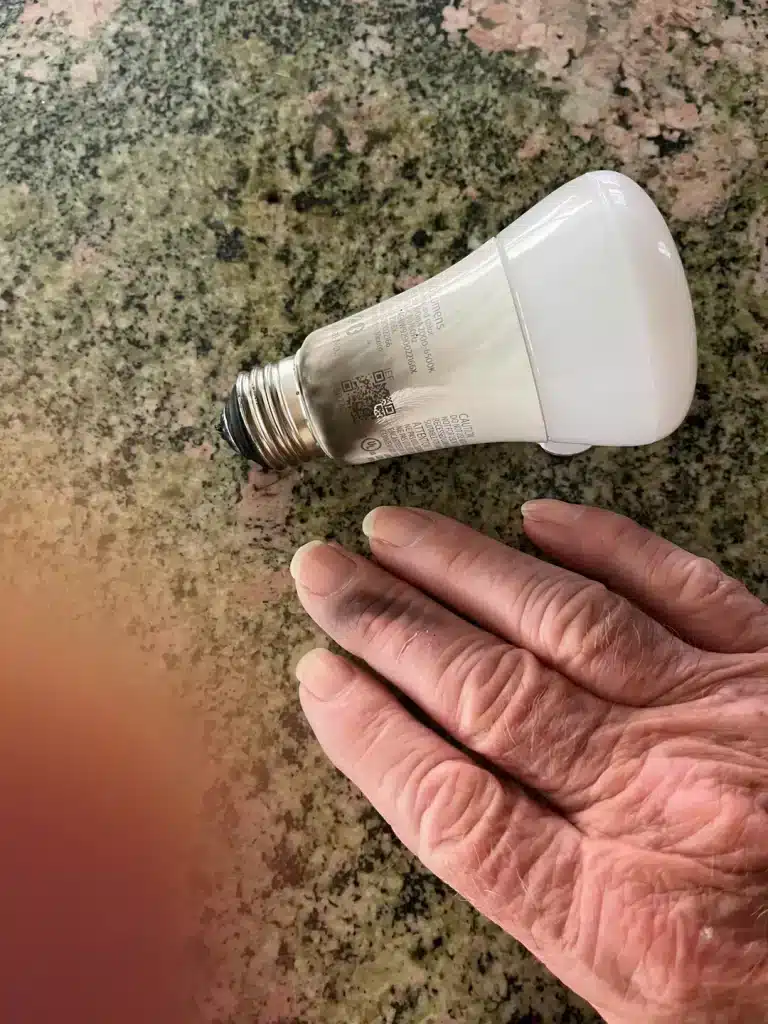 Broken Hue bulb due to unmatched voltage, with a finger showing signs of burn