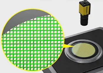 Close-up image of a yellow Cognex camera mounted beside a circular green mesh filter on a black base, with a yellow arrow highlighting the filter for industrial vision applications.