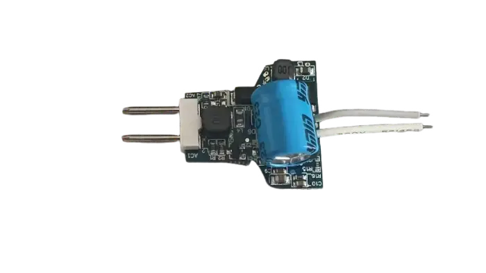 Close-up of a green printed circuit board with a prominent blue cylindrical capacitor, connected white LED strips, and various electronic components used in lighting electronics.