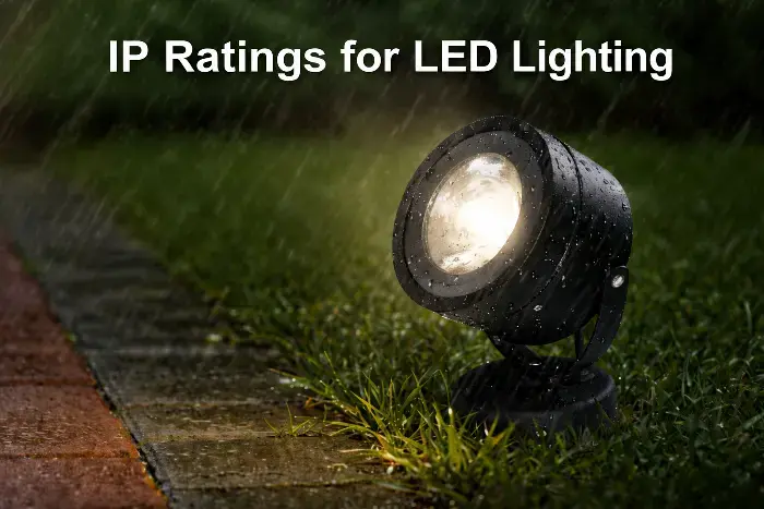Black LED spotlight mounted on grass in rainy garden, emitting bright light with water droplets, showcasing IP rating for outdoor durability.