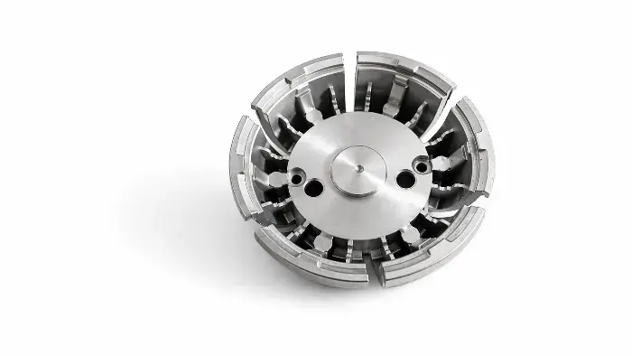 Close-up of a shiny silver circular metal part with radial blades and slots, isolated on white background for accessibility.