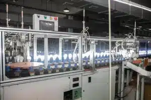 Factory automation system with rows of glowing light bulbs on a manufacturing assembly line machine.