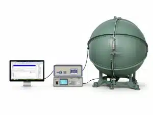 A computer monitor connected to electronic devices and a large green spherical chamber in a laboratory setting.